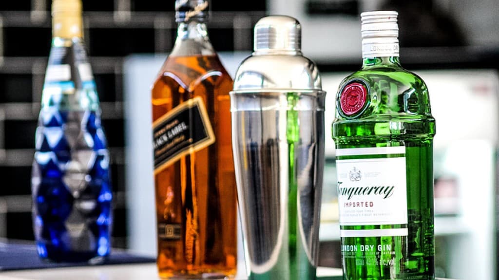 A row of premium spirits bottles and a cocktail shaker on a bar